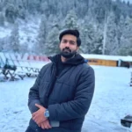 A man wearing a watch stands amidst snow, illustrating both fashion and a cold environment.